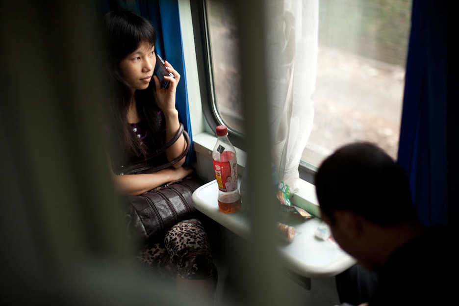 Woman talking on a cell phone on a train to Zhengzhou, China.