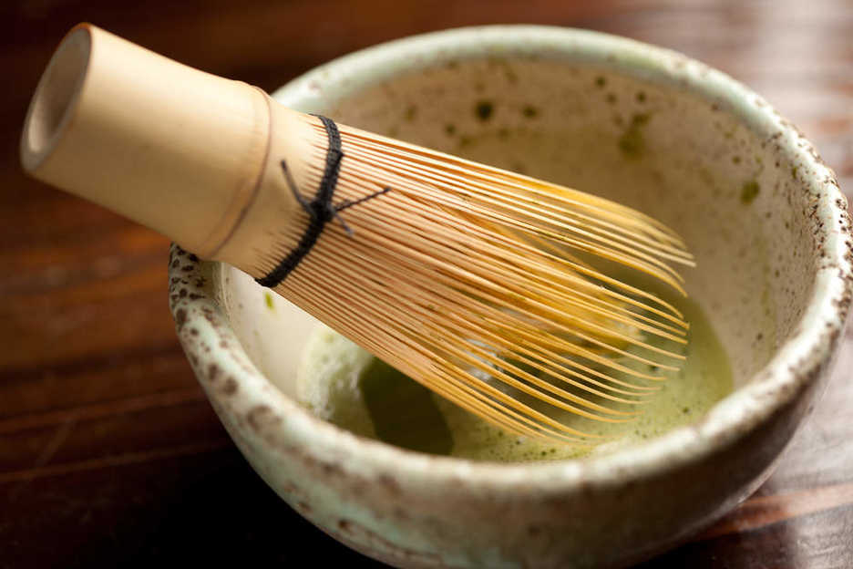 Mixing matcha with a chasen, a bamboo tea whisk.
