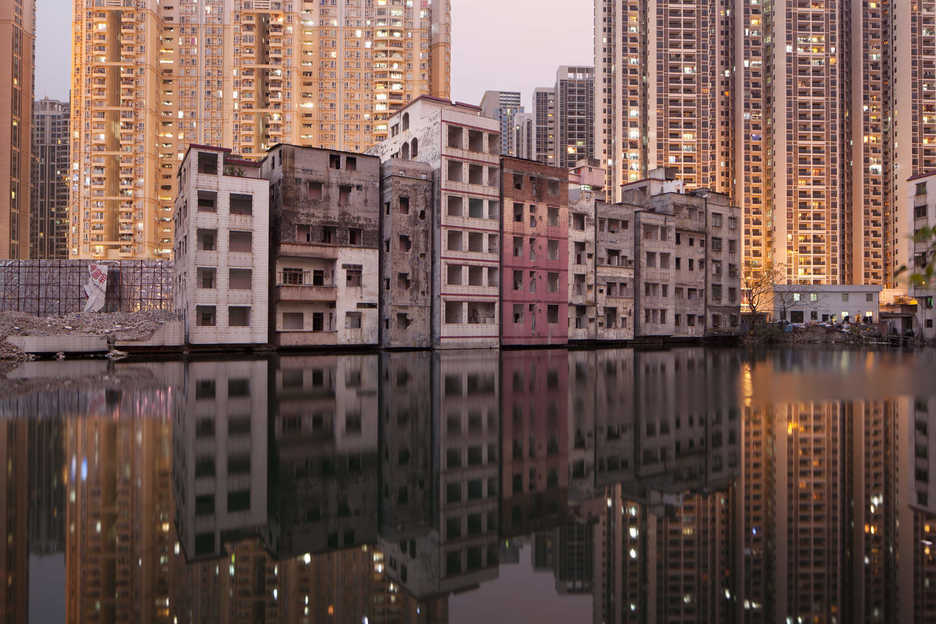 A row of partially-demolished apartment buildings line a lake in Tianhe District, Guangzhou, China