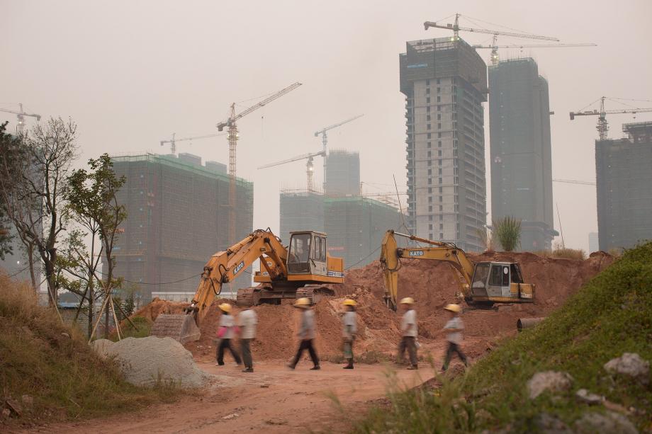 Workers walk through a construction site in Pazhou, Haizhu District, Guangzhou
