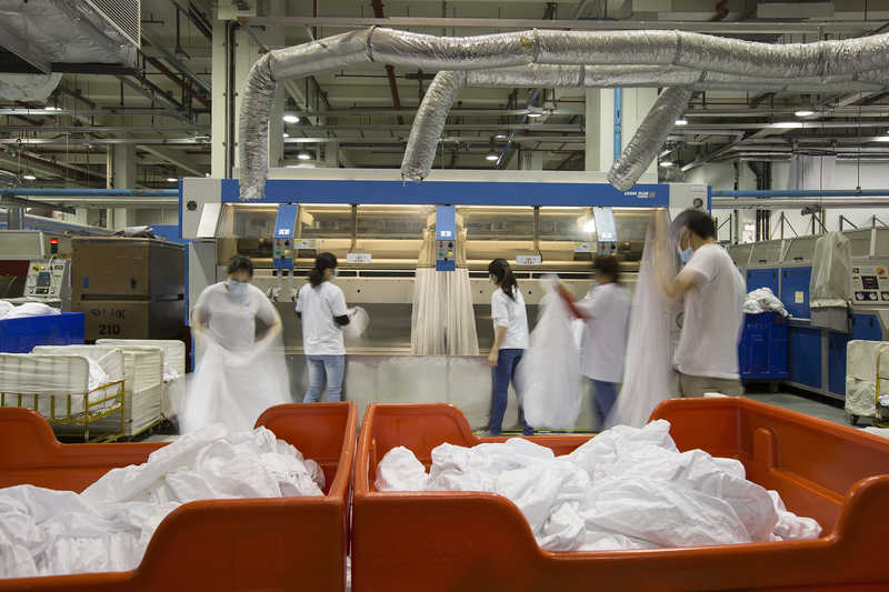 Workers launder hotel linens at Seng San Enterprises in Coloane, Macau, China.