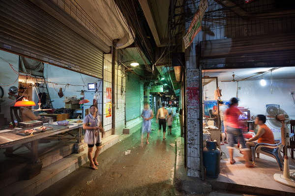 People walk through a crowded alleyway in Yuancun village