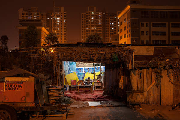 A man reads in a construction site shelter in Huangbian, Baiyun District