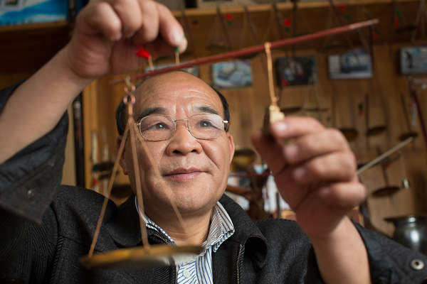 A scale maker poses with a miniature scale at his shop