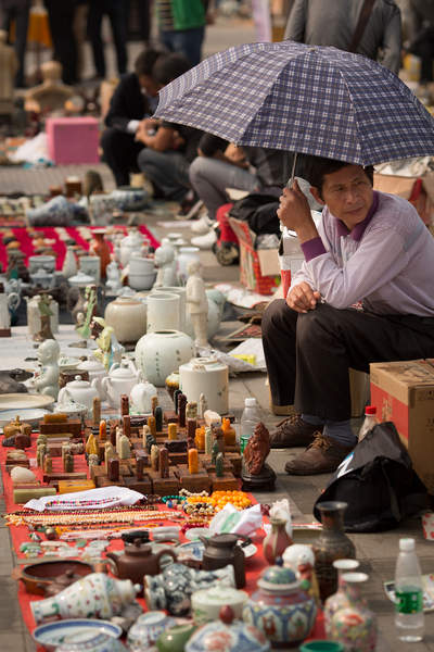 A vendor sits under an umbrella at the Changsha antiques market