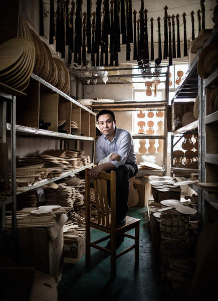 A violin maker poses in a storage room at Noble Heart Violins