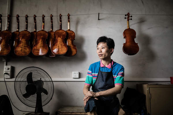 A violin maker poses in Guangzhou at Noble Heart Violins