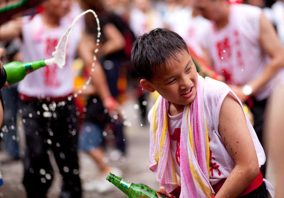 A young Drunken Dragon dancer helps splash Tsingtao beer about
