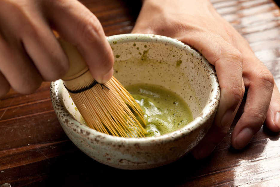Mixing matcha with a chasen, a bamboo tea whisk.
