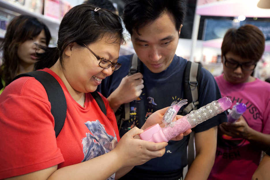 Asia Adult Expo attendees examine a vibrating dildo at a trade fair booth