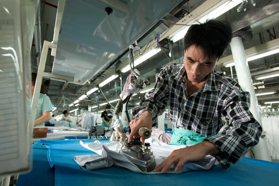 A worker irons a shirt at the Lever Style factory in Guan Lan, Shenzhen, China