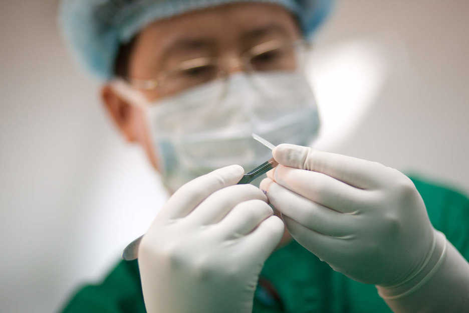 Physician Li Yujie shapes a nose insert with a scalpel in China