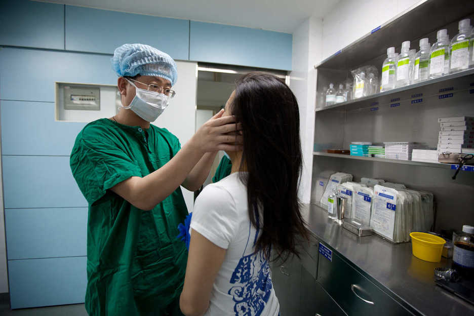Li Yujie inspects a patient after performing an operation to enlarge her nose