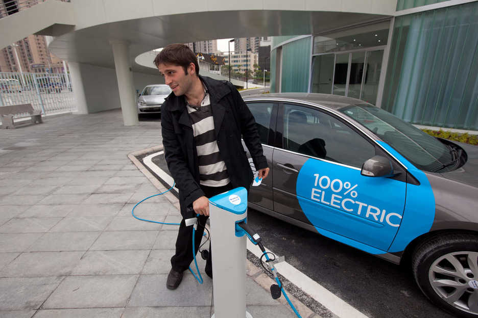 A man charges an electric car in Guangzhou, China