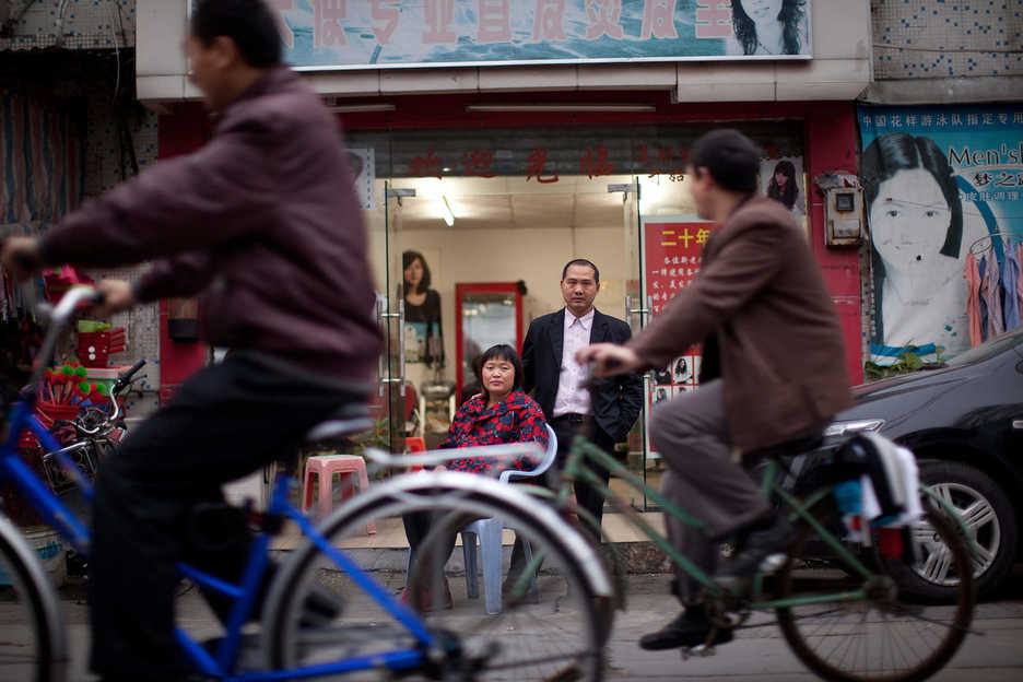 Peng Haiying and her husband Zhu DaoLin pose outside their hair salon in Dongguan, Guangdong Province, China