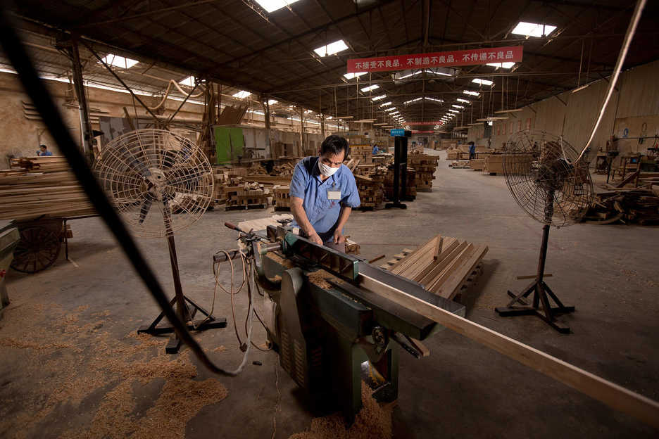 A worker planes a board at the Hongyuan furniture factory in Panyu, Guangzhou