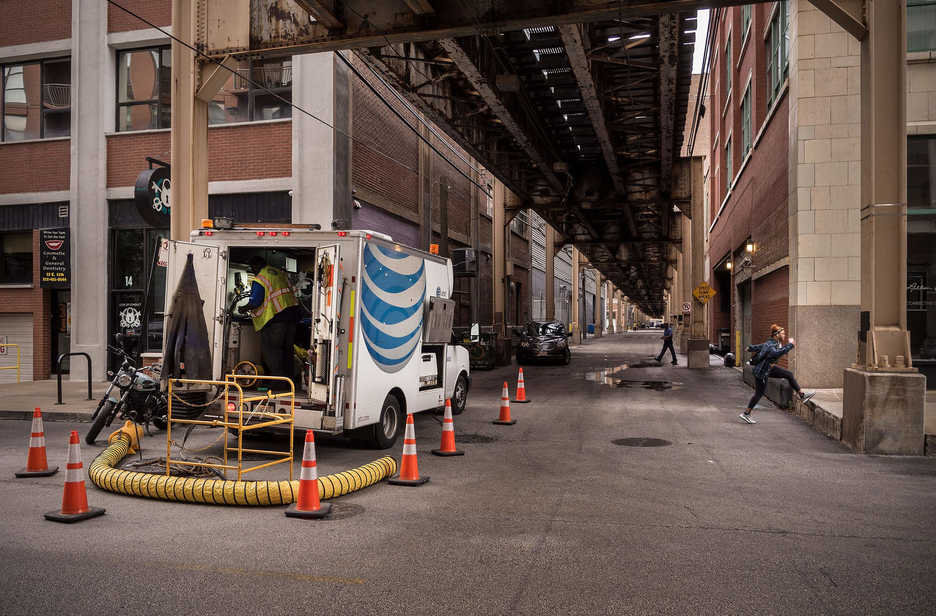 A phone company crew works under train lines