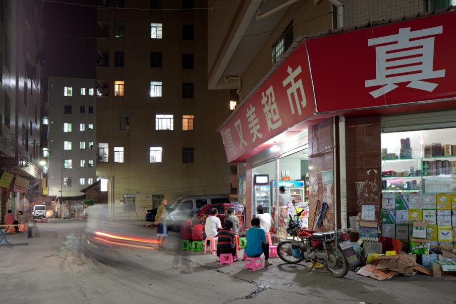 People watch a TV set outside a shop in Yongtai Village