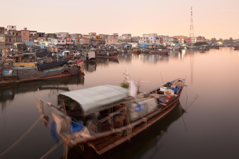 A fishing village is illuminated at dusk along the Pearl River in Guangzhou, China.