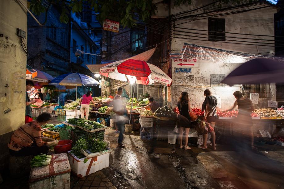 People shop at a vegetable market in Liwan